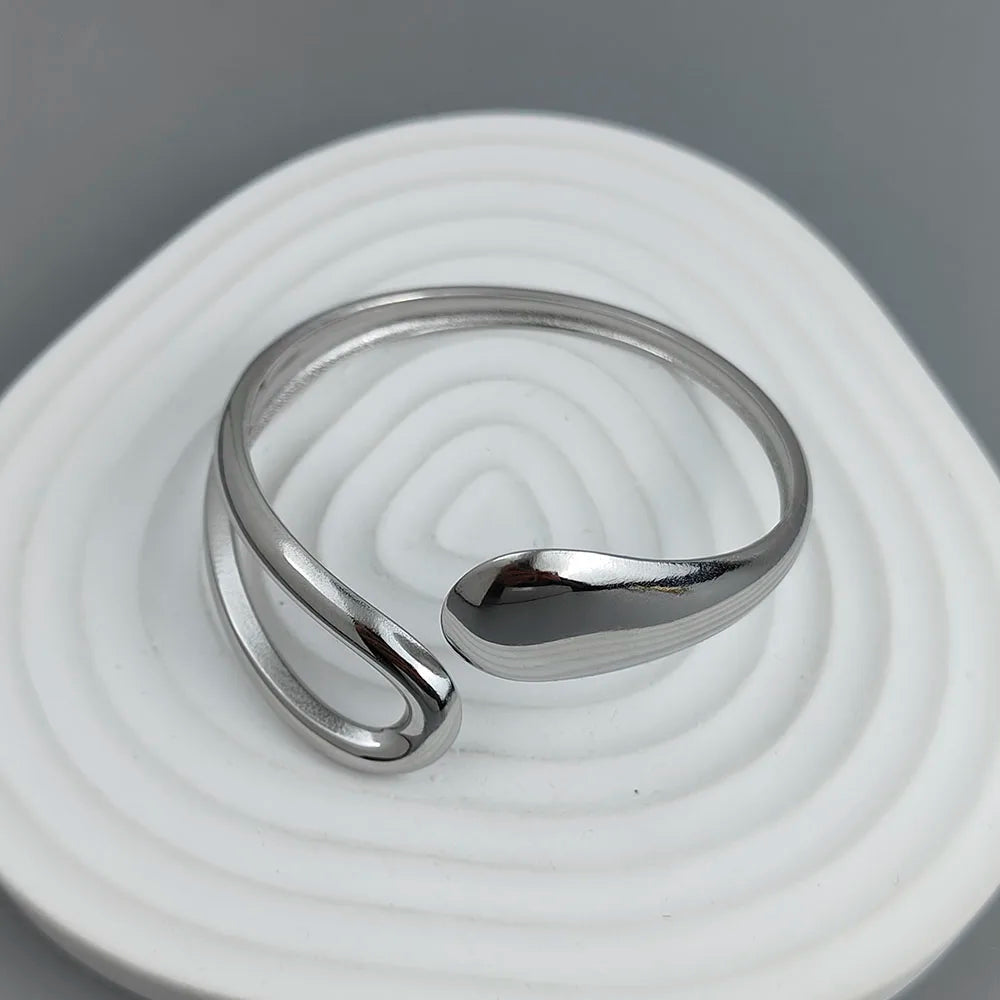 Adjustable silver-plated cuff ring with modern minimalist open loop design on a gray background