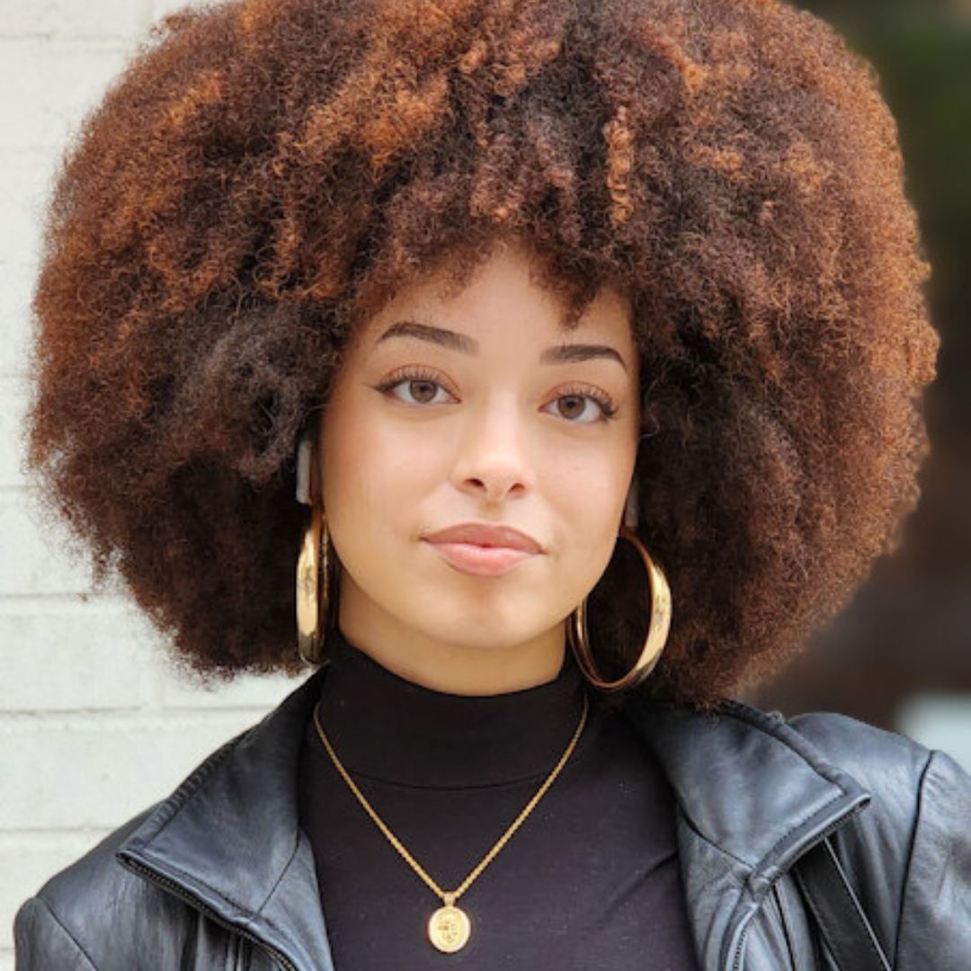 Woman with large afro wearing gold hoop earrings and a black turtleneck from BAD Hair Uprooted