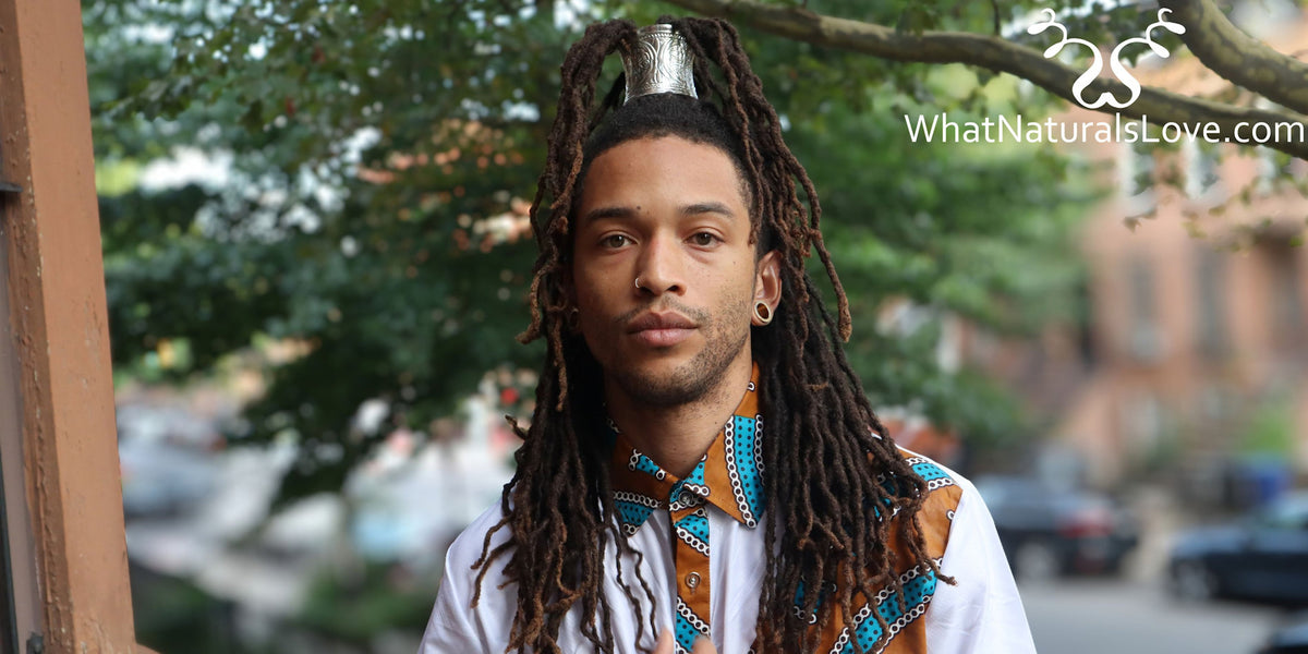 A Black man with long dreadlocks wearing a silver ponytail hair cuff in his hair. The text 'WhatNaturalsLove.