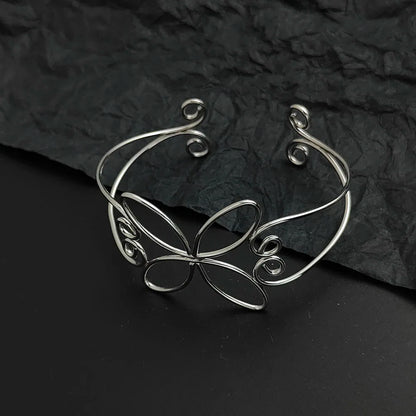 the silver bloom hair cuff laying on a black background