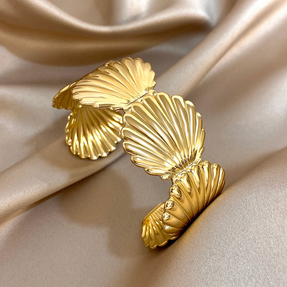 Gold hair cuff with elegant shell-shaped design, displayed on champagne satin background.