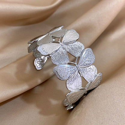 Silver butterfly hair cuff with intricate wing engraving, displayed on satin fabric.