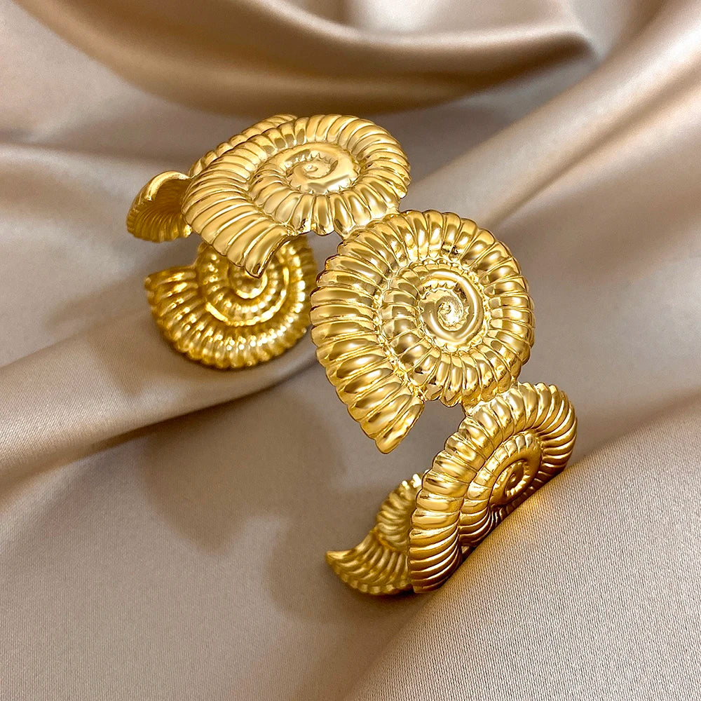 Gold hair cuff with bold spiral shape, inspired by seashell swirls and oceanic textures.