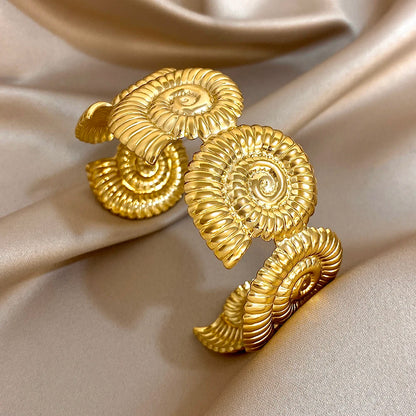 Gold hair cuff with bold spiral shape, inspired by seashell swirls and oceanic textures.
