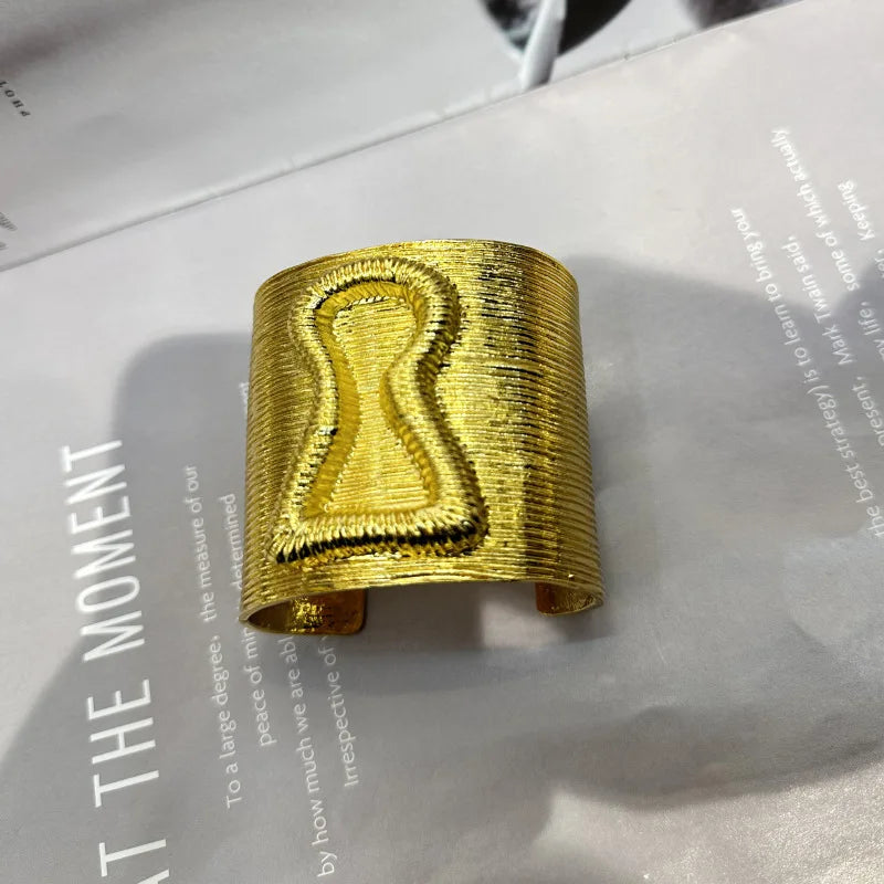 Gold keyhole hair cuff with bold exaggerated form and engraved keyhole detail.