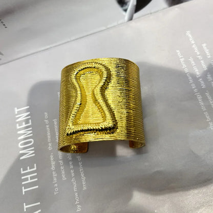Gold keyhole hair cuff with bold exaggerated form and engraved keyhole detail.