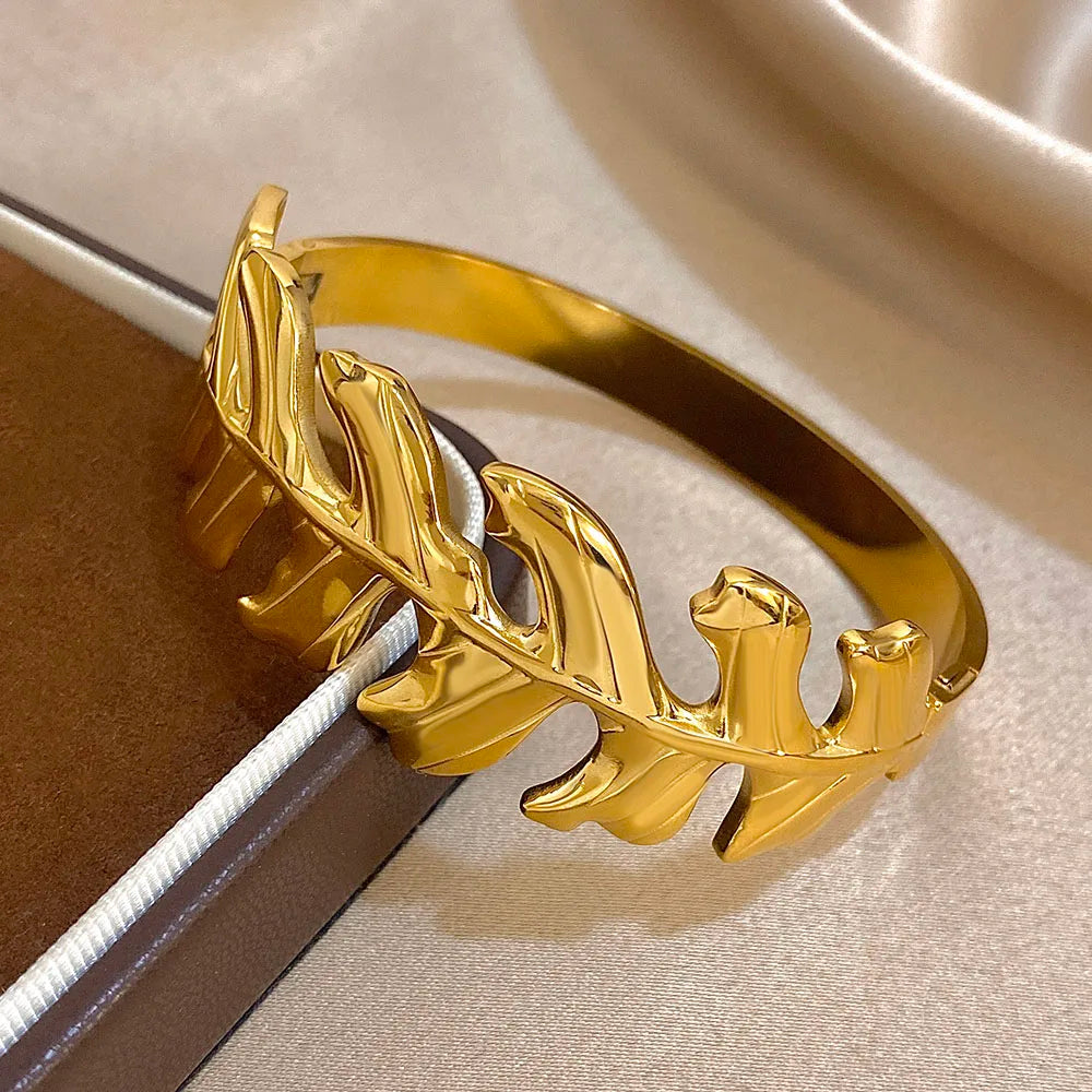 Gold Leaf Hair Cuff with leaf design, displayed on beige satin fabric from side angle