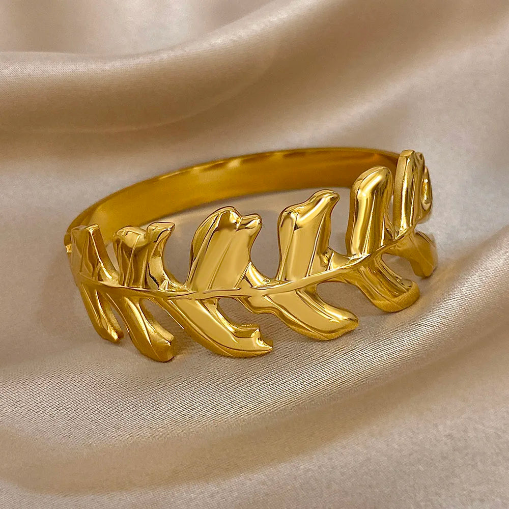 Gold Leaf Hair Cuff with leaf design, displayed on beige satin fabric from the front angle