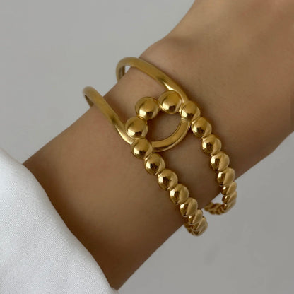 Gold beaded cuff bracelet with round decorative design, worn on wrist for a modern minimalist look