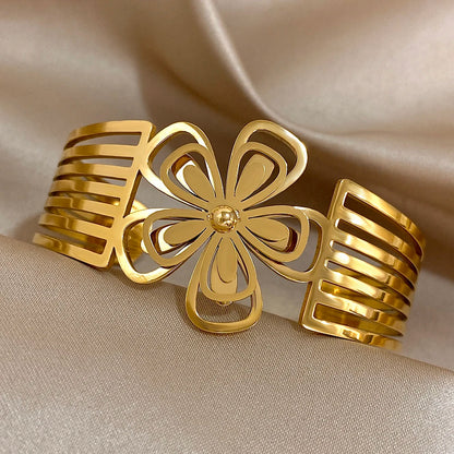 Gold hair cuff featuring a hollow flower centerpiece with striped cut-out band.