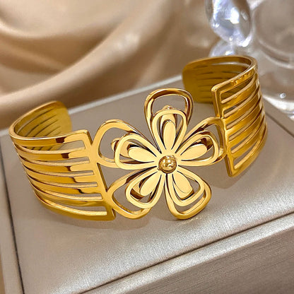 Gold floral hair cuff with openwork petal design and striped band, displayed on a satin background.