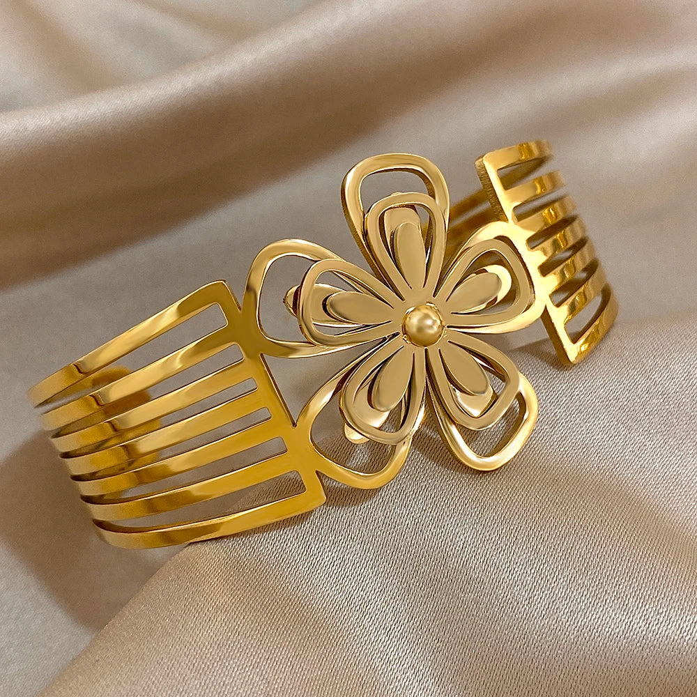 Full view of a gold hair cuff with a hollow flower at the center and striped band edges.