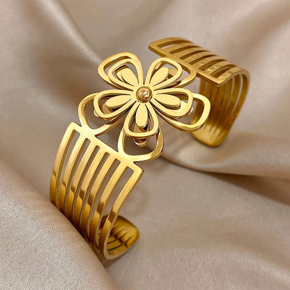 Elegant gold hair cuff with hollow flower petals and geometric open band, shown at an angle.