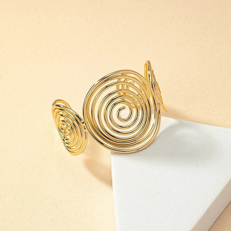 Gold geometric spiral hair cuff with large center spiral and two side spirals, front angle view.
