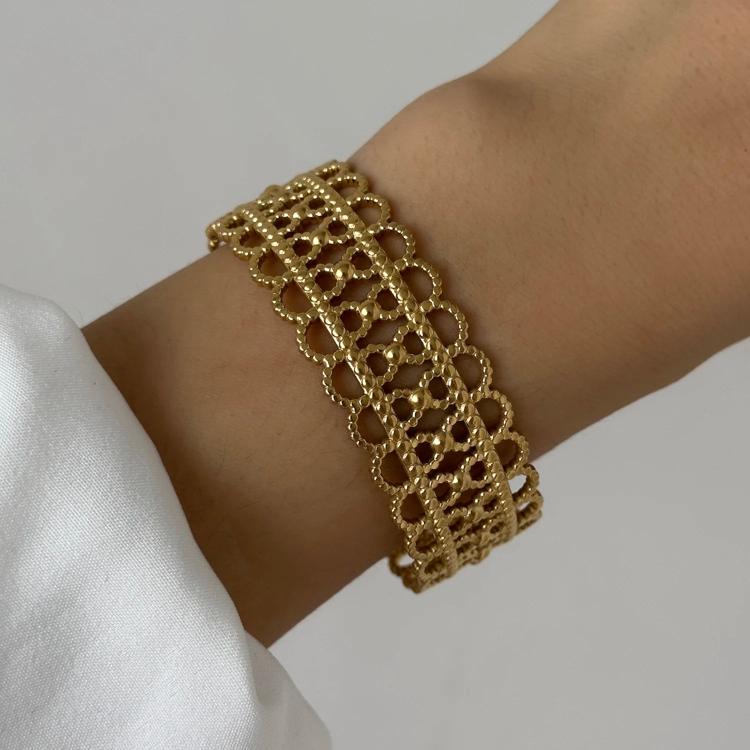 Gold lattice cuff bracelet with intricate lace-style pattern, creating a vintage elegant look