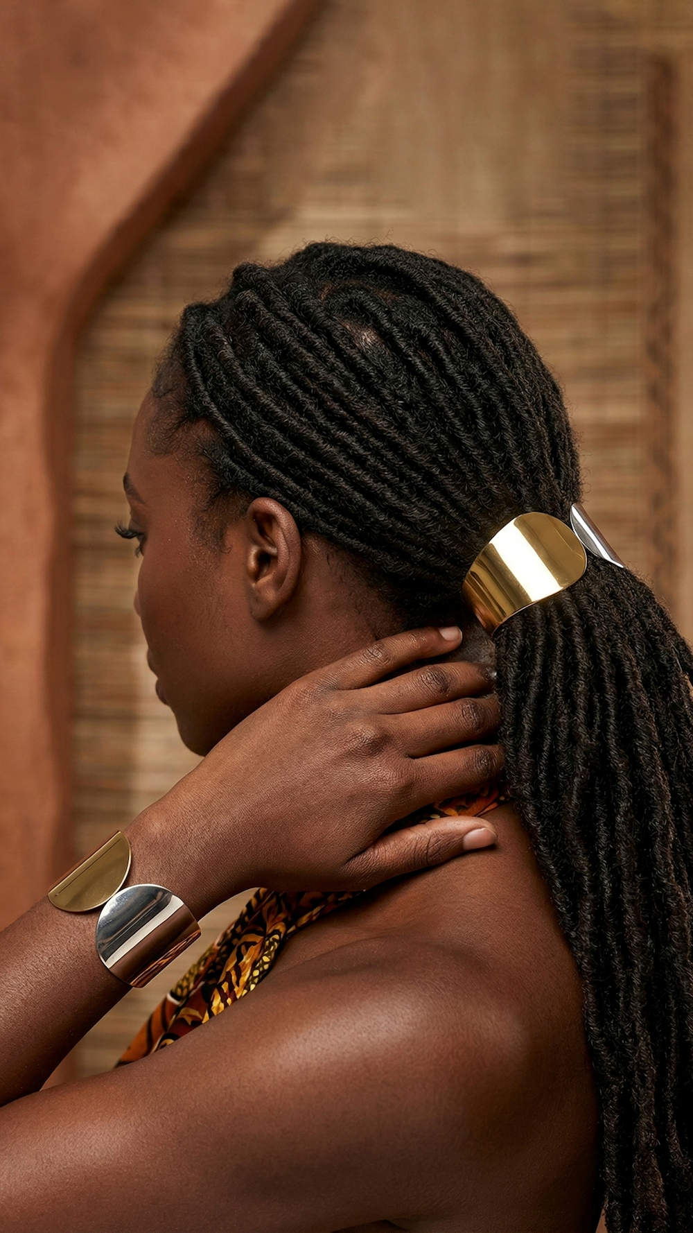 Black woman with her locs in an low ponytail held by the silver ponytail holder