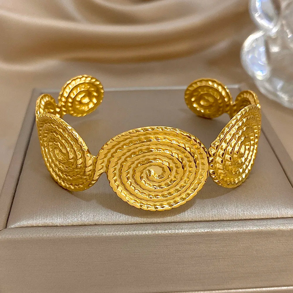 Centered view of gold spiral textured hair cuff with intricate circular detailing.