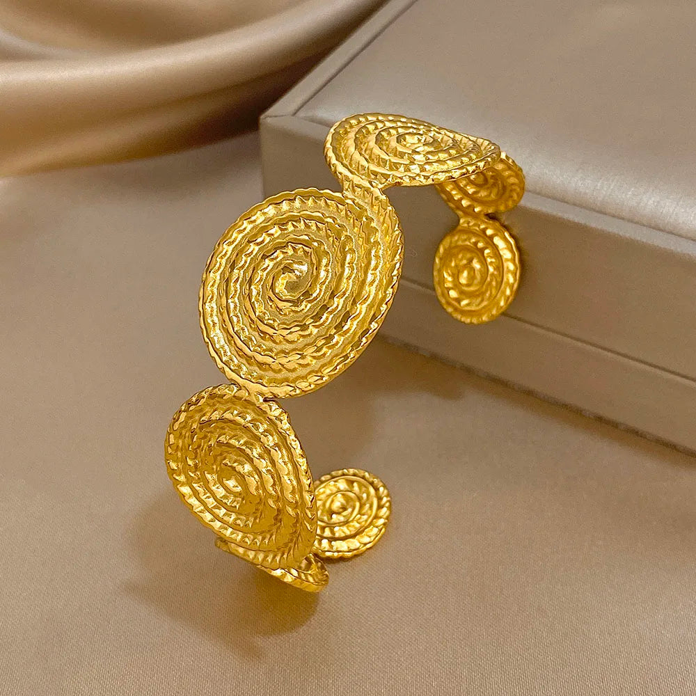 Gold spiral hair cuff with raised textured surface, displayed on a soft background.