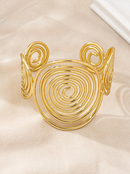 Gold swirl hair cuff shown at an angle, featuring a large central spiral and two side spirals.