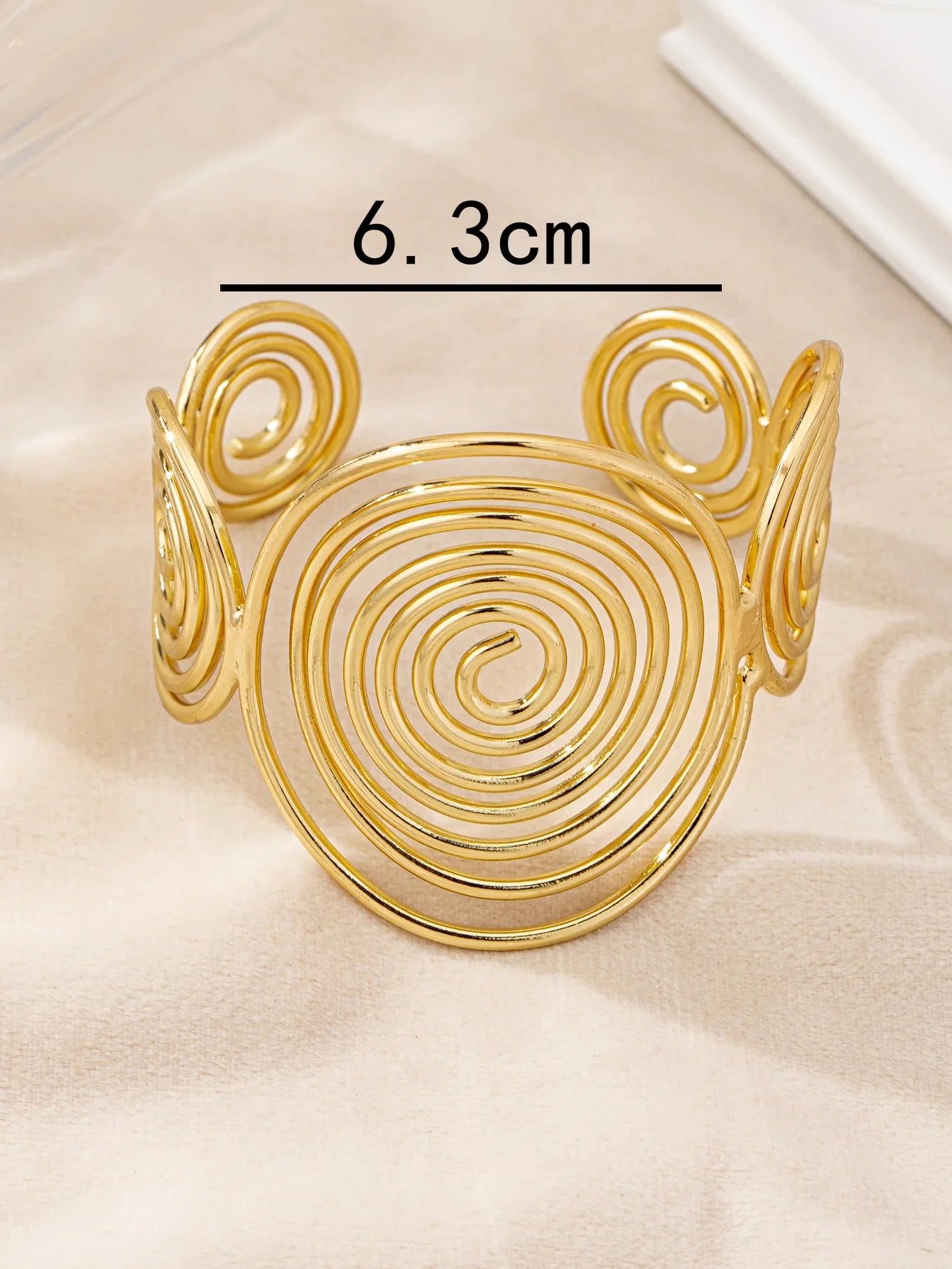 Gold swirl hair cuff with 6.3 cm diameter, shown with measurement on a light fabric surface.
