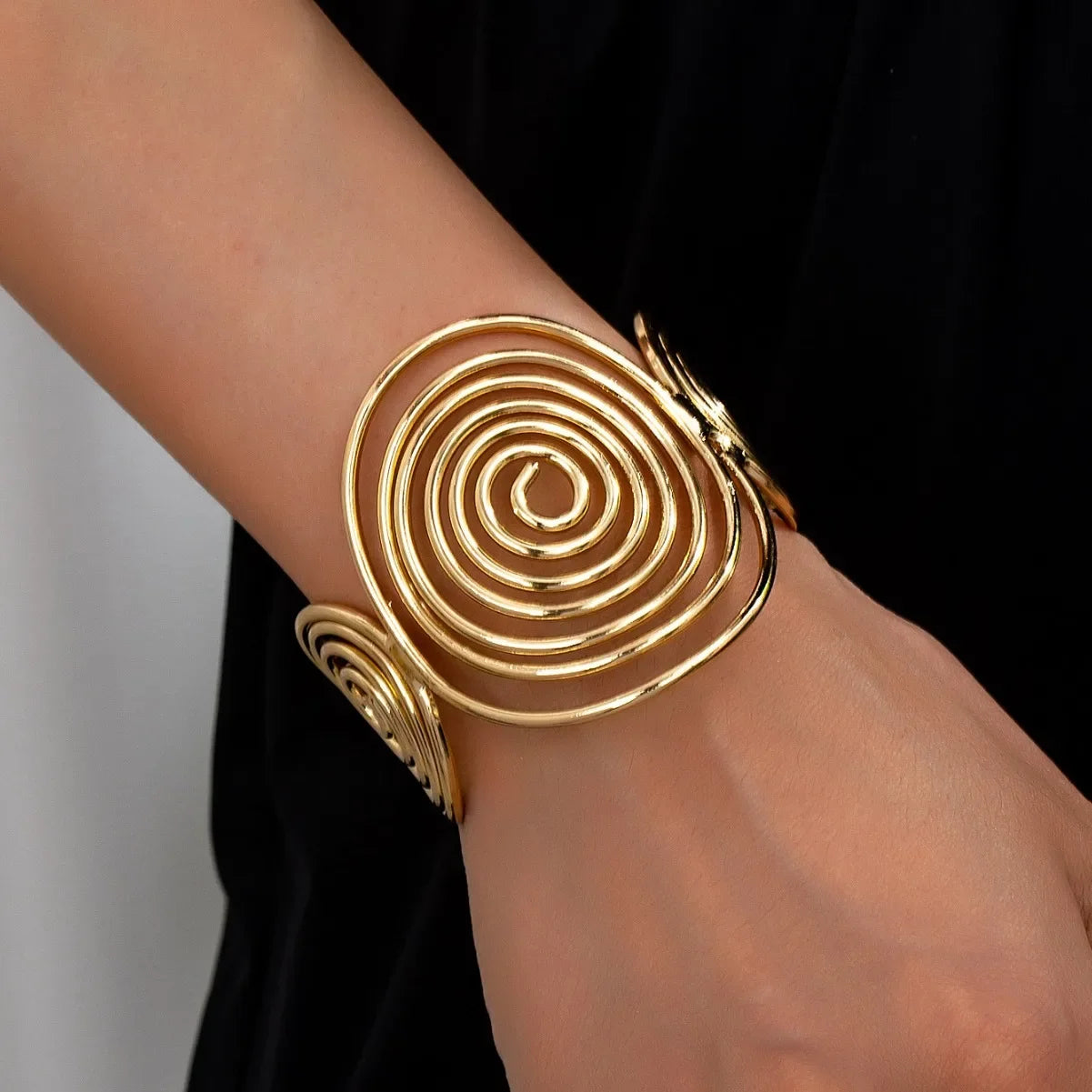 Gold swirl hair cuff with elegant spiral design, styled on wrist to show fit and shine.