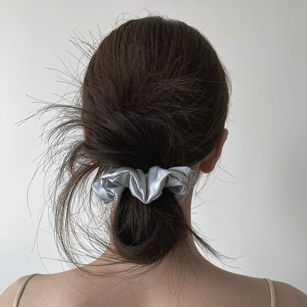 Woman with dark hair wearing an ivory mulberry silk scrunchie in a low bun. Soft silk hair tie for a smooth, damage-free hold and elegant style.