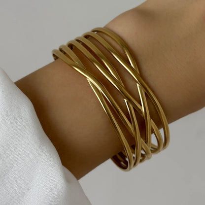 Elegant layered gold wave bangles wrapped around a wrist, creating a chic and modern minimalist look