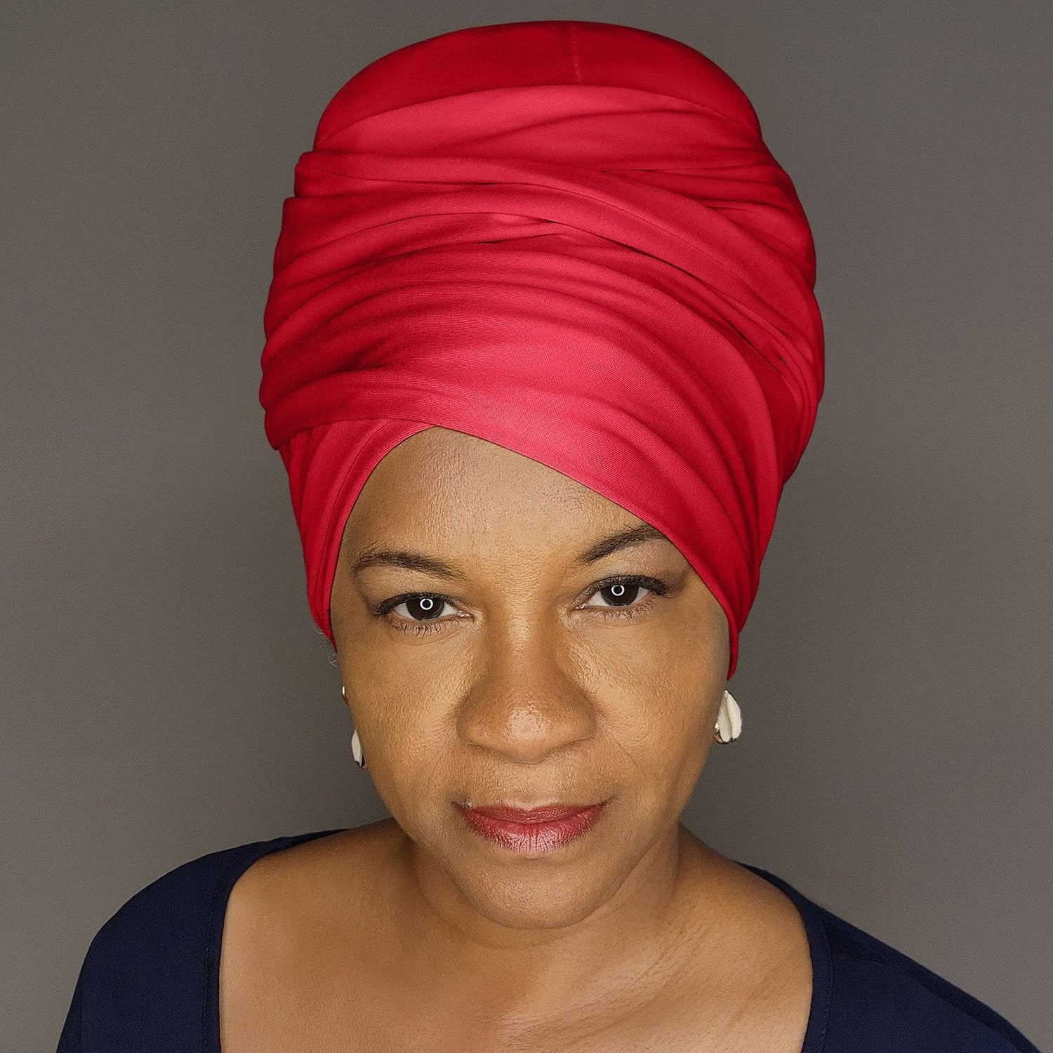 Woman wearing a red headscarf against a gray background
