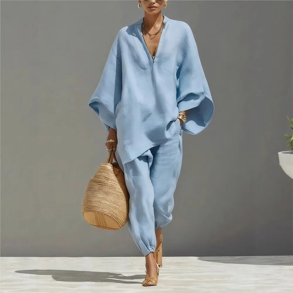 Woman in a light blue outfit holding a woven bag against a gray background