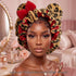 A woman wearing a leopard print satin-lined sleep bonnet with large red bows, posed in a pink bedroom setting with a vanity mirror and cosmetics in the background.