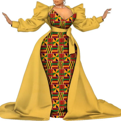 Yellow satin overlay gown with a colorful geometric print panel, puff sleeves and a long train, on a white background.