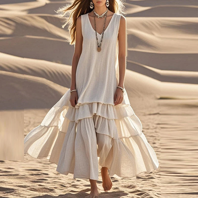Woman in a flowing white dress standing on sand dunes
