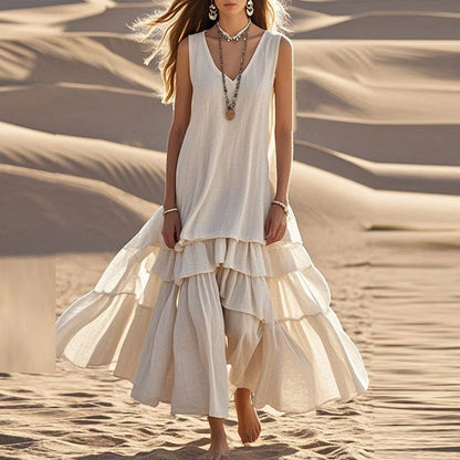 Woman in a flowing white dress standing on sand dunes