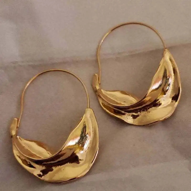 Pair of gold Fulani earrings or Sula on a neutral background
