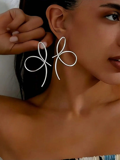 Close-up of a person wearing a silver bow-shaped earring.