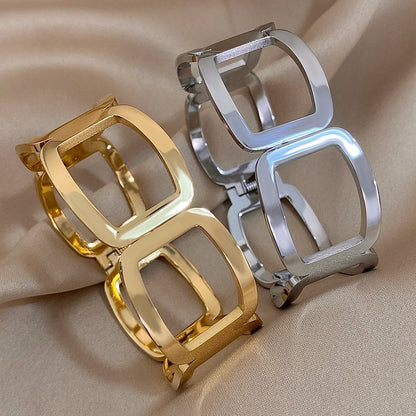 Gold and silver geometric link cuffs side by side on beige satin