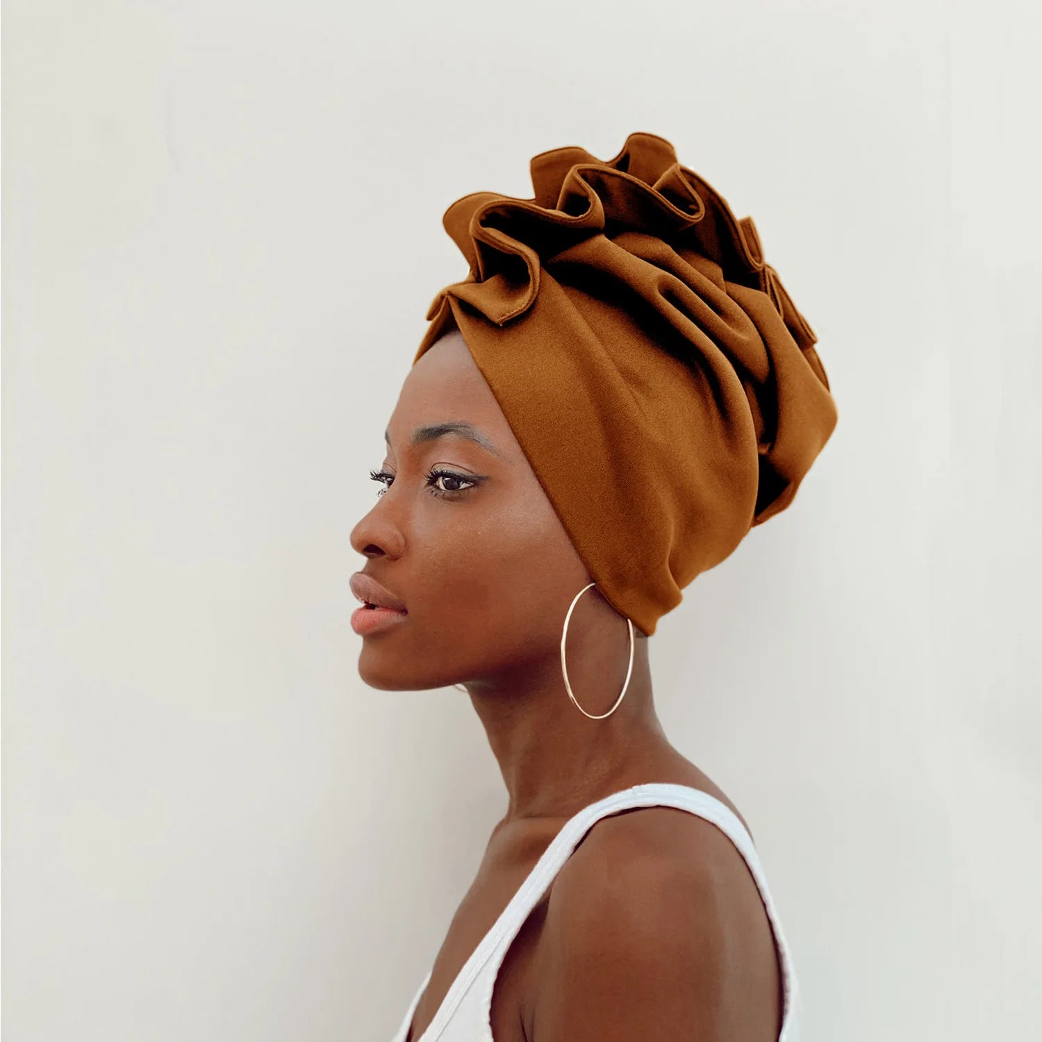 Woman wearing a brown headscarf against a white background
