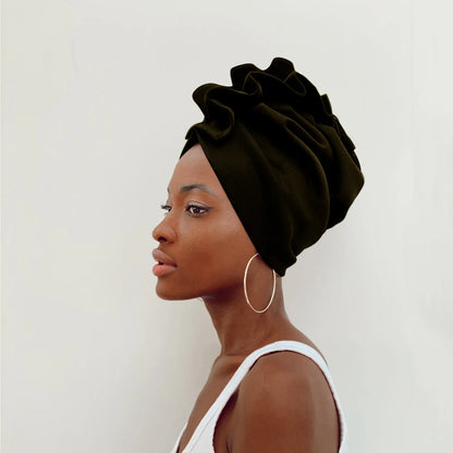 Woman wearing a dark green headscarf against a white background