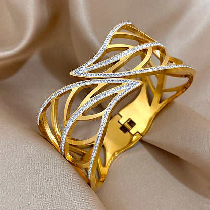 Side view of a gold leaf crystal cuff showing the hinge and spring closure, on champagne satin