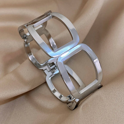 Silver open-frame link cuff with a hinge and spring closure, on beige satin