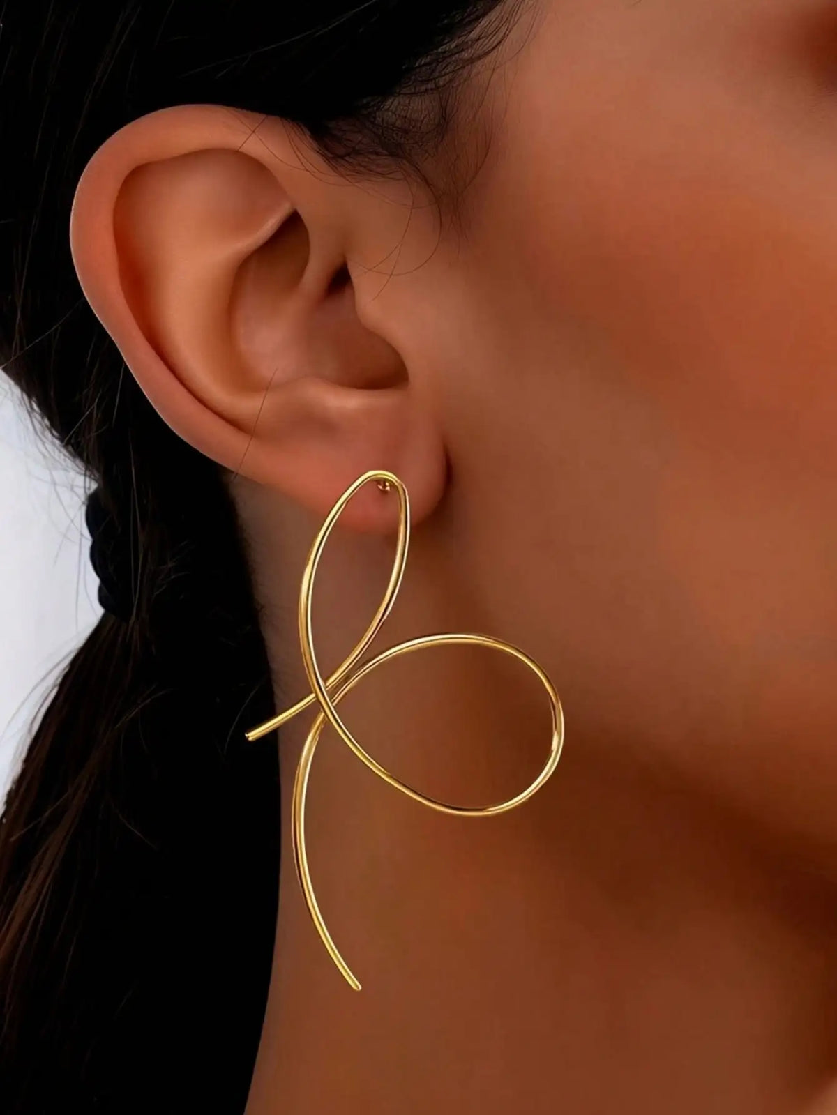 Gold hoop earring worn by a person with a blurred background