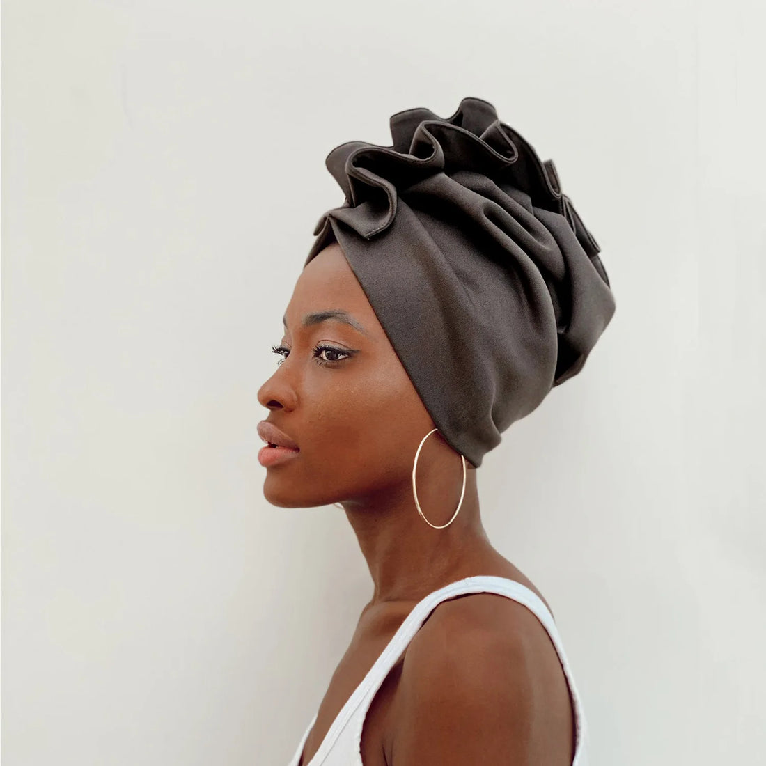 Woman wearing a gray headscarf against a white background