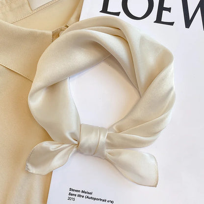 Beige silk scarf tied in a knot on a white surface with &