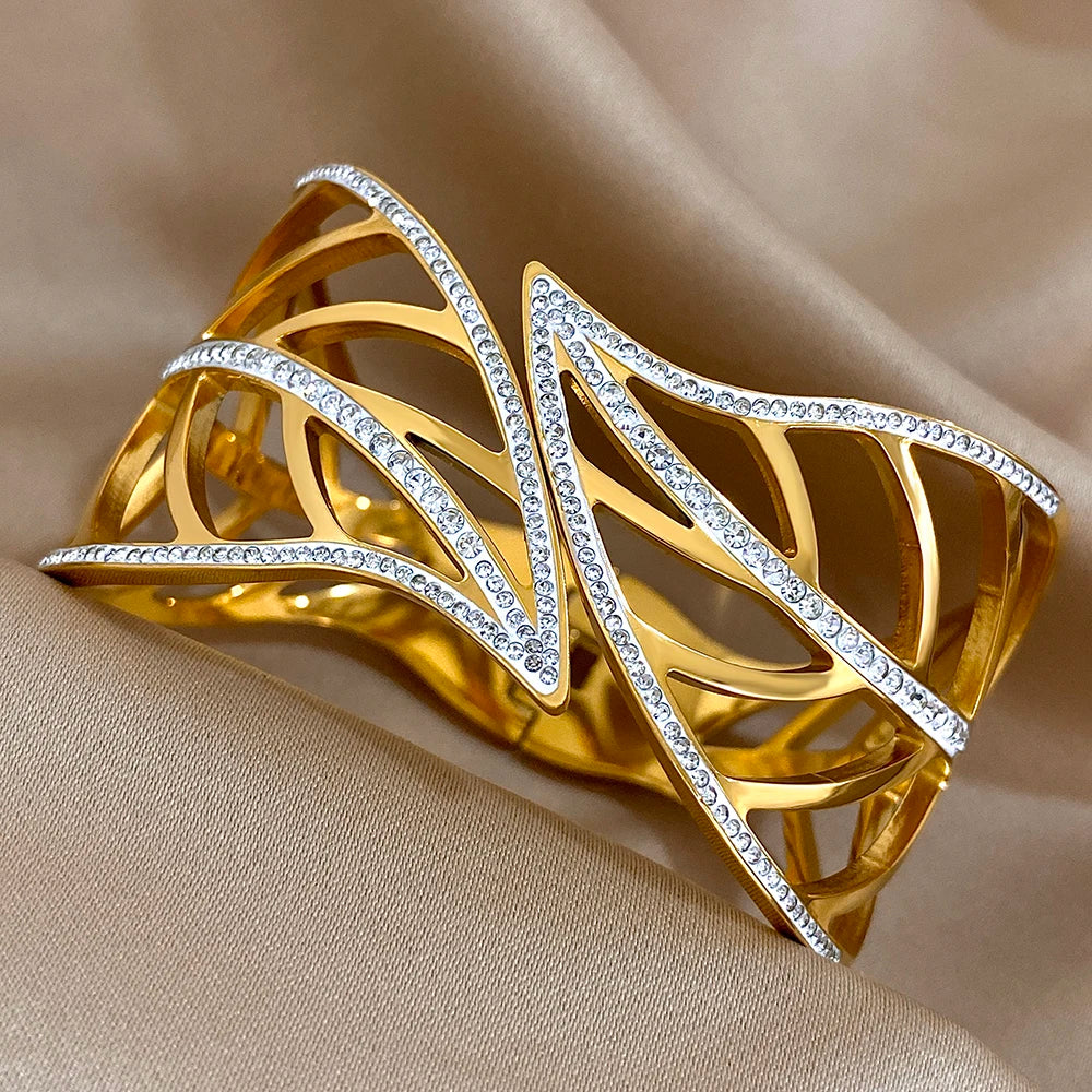 Close-up of a gold openwork leaf cuff with sparkling crystal-lined veins, on beige satin