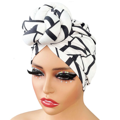 Stylish patterned knot turban headwrap in black and white geometric design, worn on a mannequin with glamorous makeup. Soft and elegant headwear.