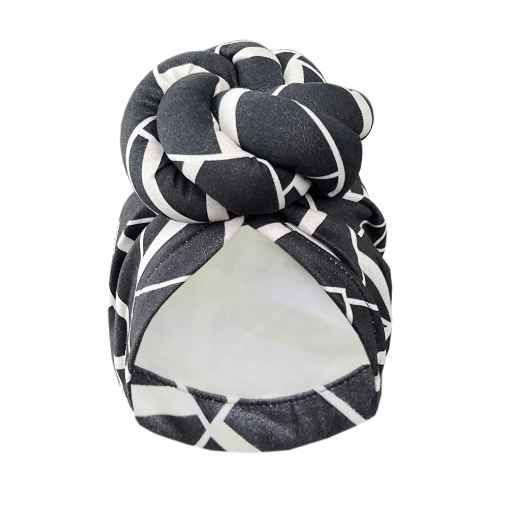 Black and white geometric patterned knot turban headwrap with a stylish twisted knot. Elegant and comfortable headwear for fashion and protection.