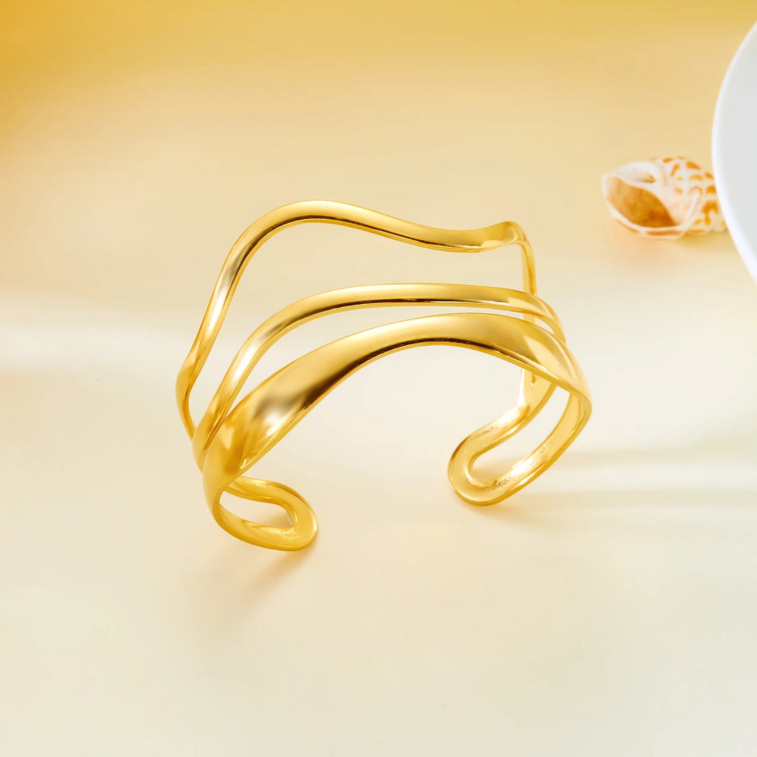 Close-up of gold geometric wide cuff bracelet with elegant wavy lines and open bangle design