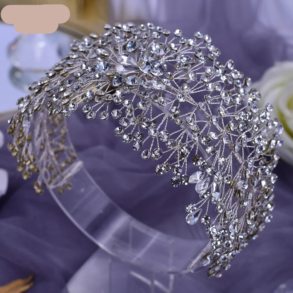 Silver crystal bridal tiara with intricate branch detailing displayed on transparent stand