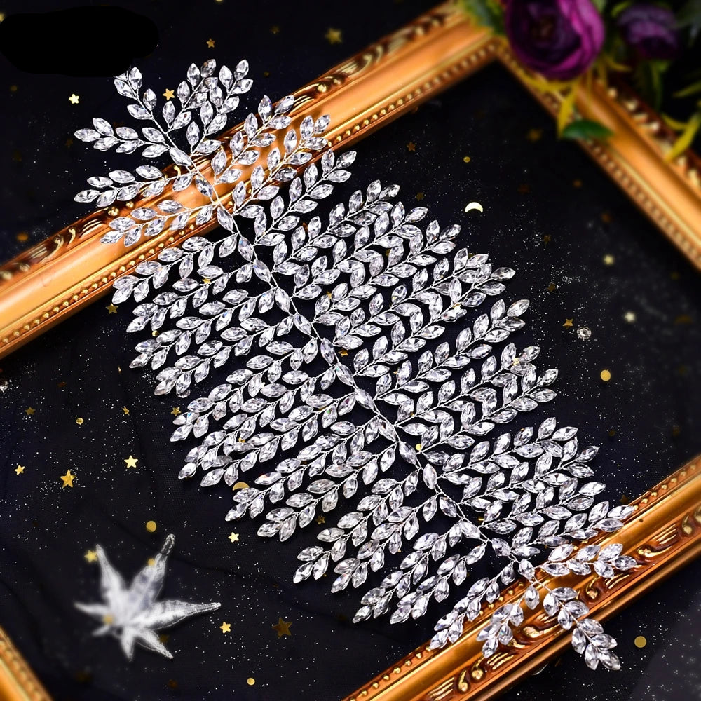 Close-up of silver bridal crown tiara with intricate leaf design, laid flat on black starry background