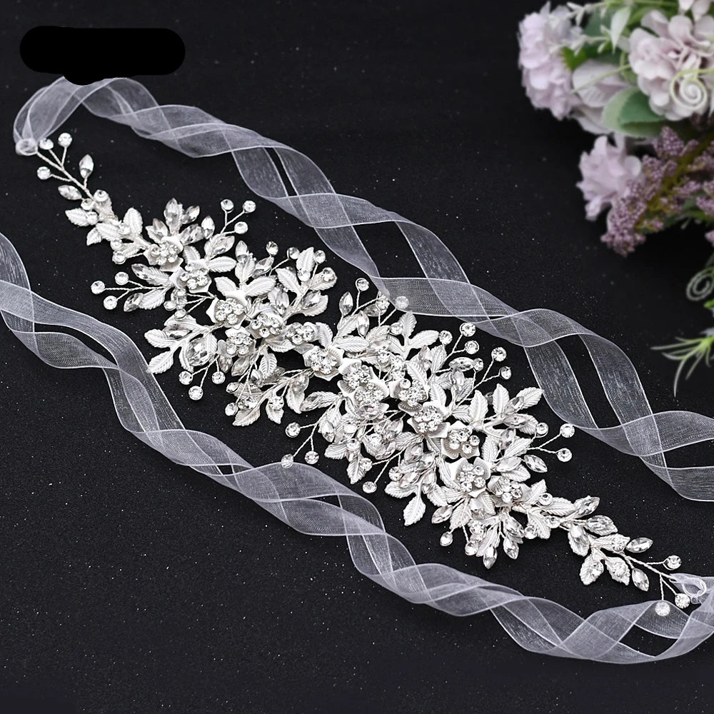 Full silver bridal headpiece with floral leaf detailing and rhinestone accents laid flat with ribbons